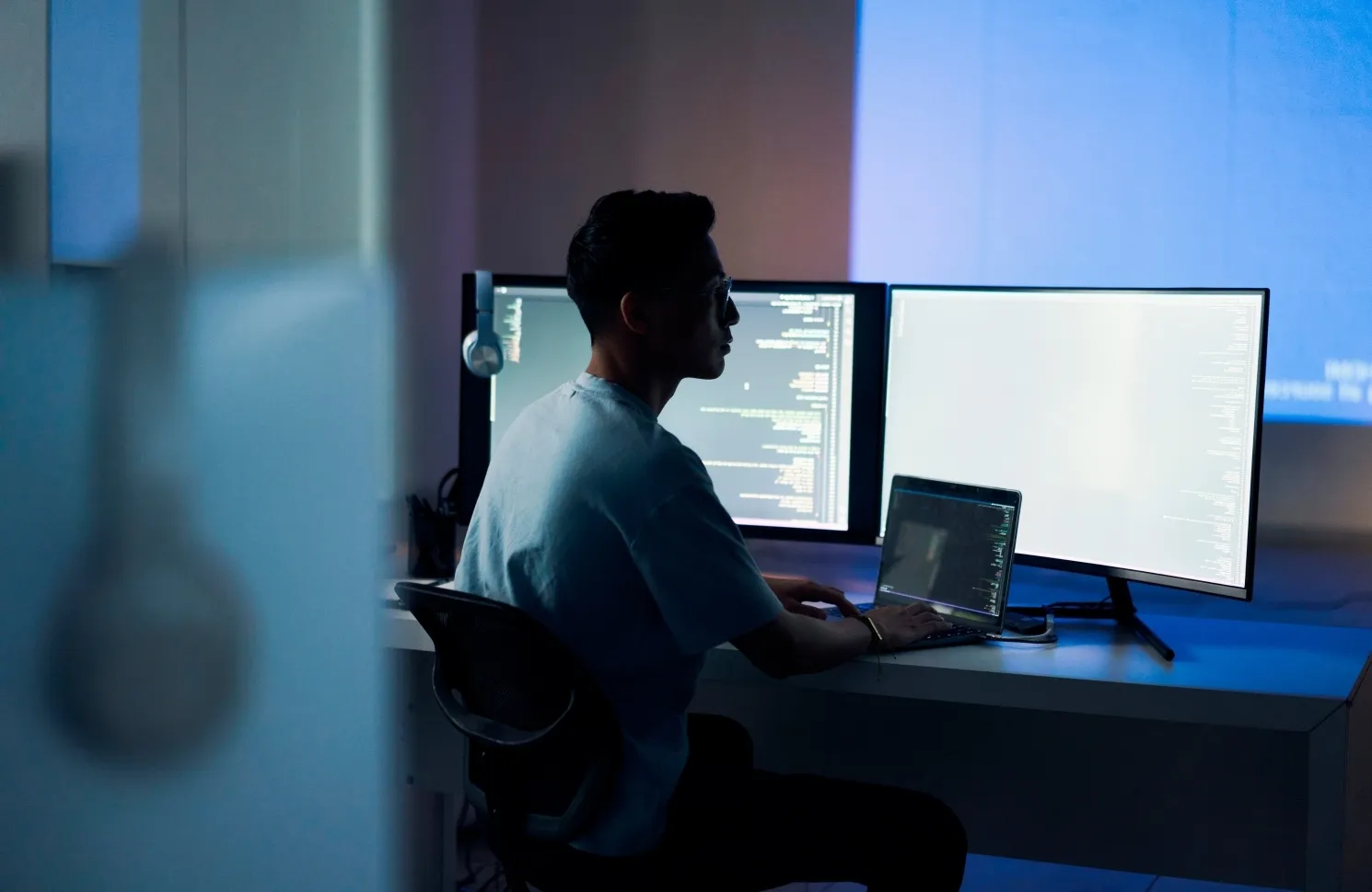 Developer sitting in front of computers reviewing code